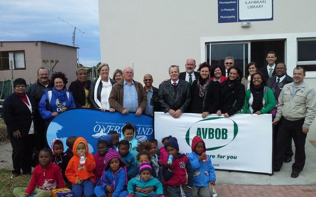 Officials of the Overstrand Municipality and AVBOB Funeral Undertakers with children of the Eluxolweni community pose happily in front of the new Eluxolweni Library, beneficiary of a substantial donation from AVBOB of library books and office materials.